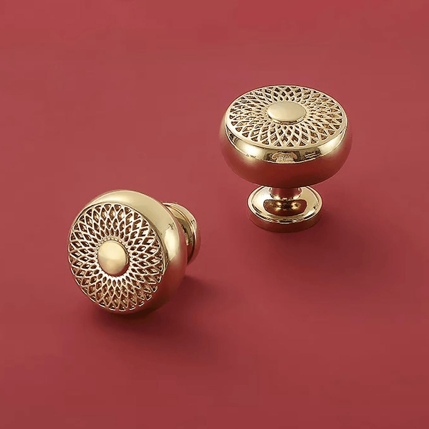 The image features a Gold Decorative round design brass knob placed on the floor against a maroon background. The knob has a circular shape and is made of brass material with a decorative design on the front. The knob is positioned on the floor, showcasing its shiny gold finish against the rich maroon backdrop. Its elegant and ornate design adds a touch of sophistication to any space. 
